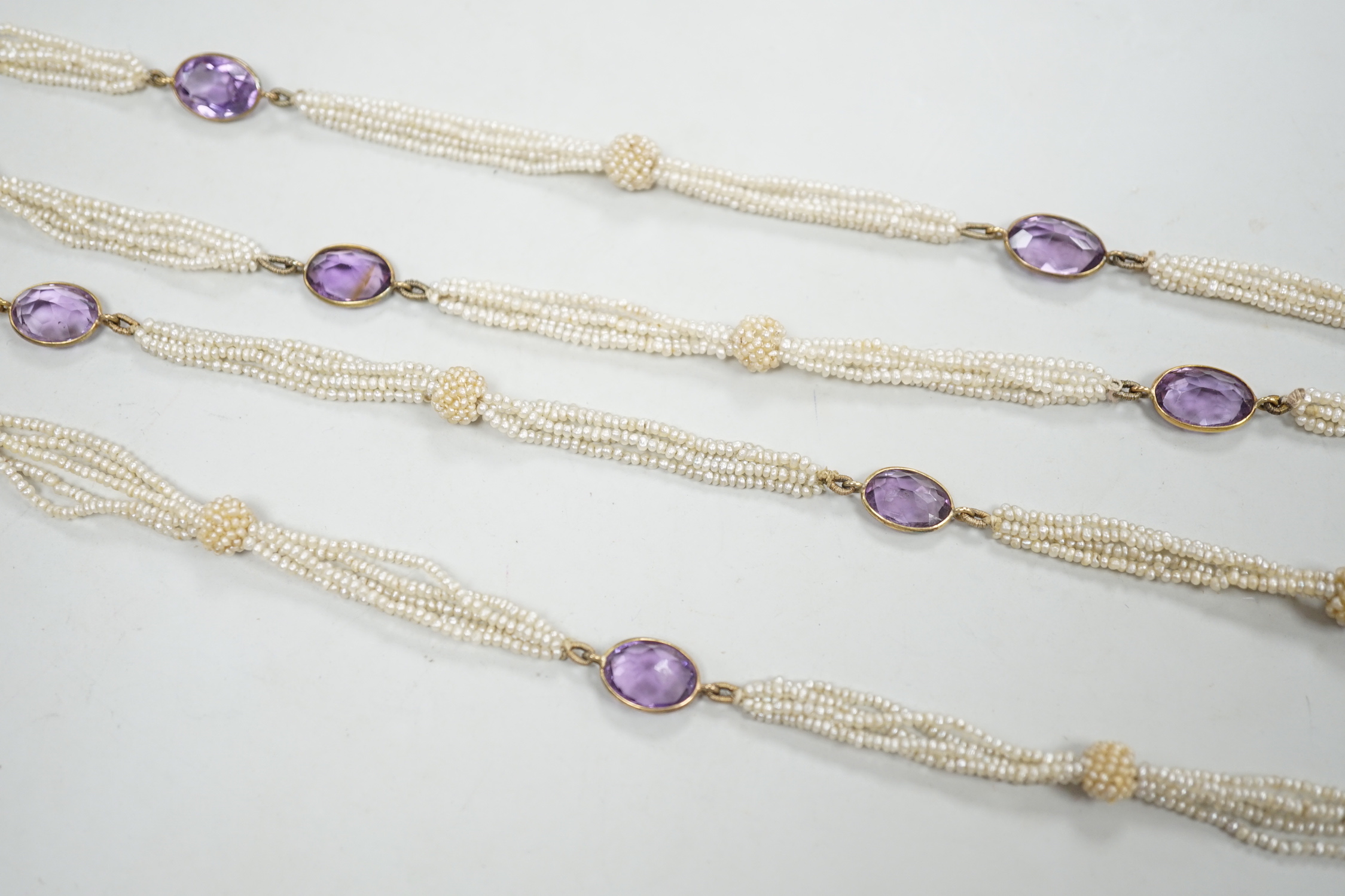 A 19th century Indian multi strand seed pearl and oval cut amethyst set long necklace, with gem set tassel drops, 166cm.